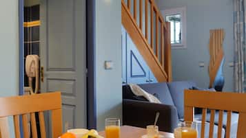 Une table à manger avec des aliments pour le petit-déjeuner, un escalier et une vue sur le salon.