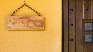 A wooden sign with a mountain landscape and the text 'La Devesa' hanging on a yellow wall. - Casa Rural Devesa in Villablino, Laciana Valley with Pool (Caboalles De Abajo)