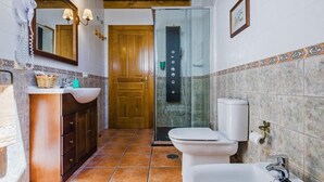A bathroom with a wooden door, a shower, a sink, and a toilet. - Casa Rural Devesa in Villablino, Laciana Valley with Pool (Caboalles De Abajo)