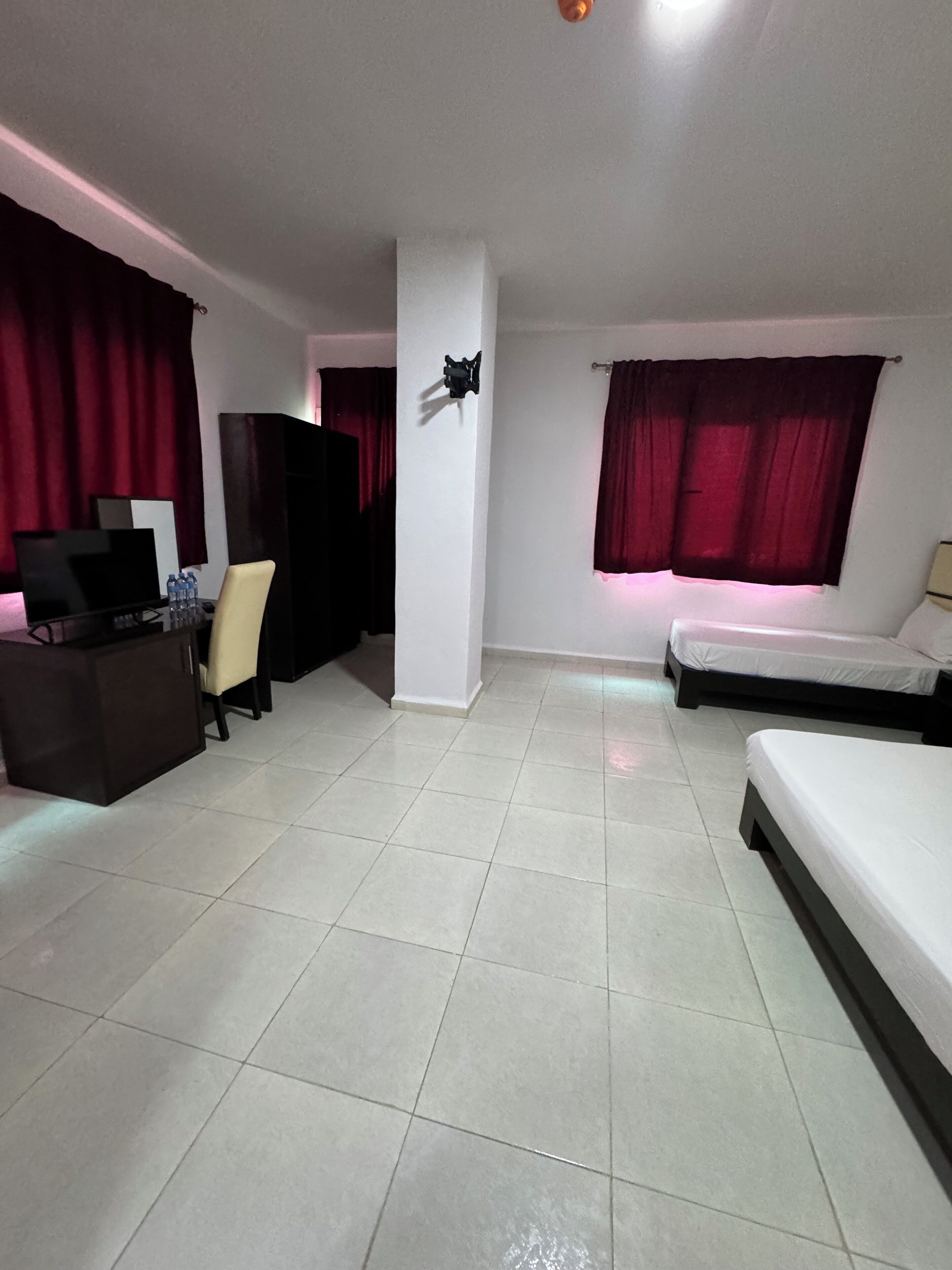 Una habitación con cama, un escritorio con silla y televisión.