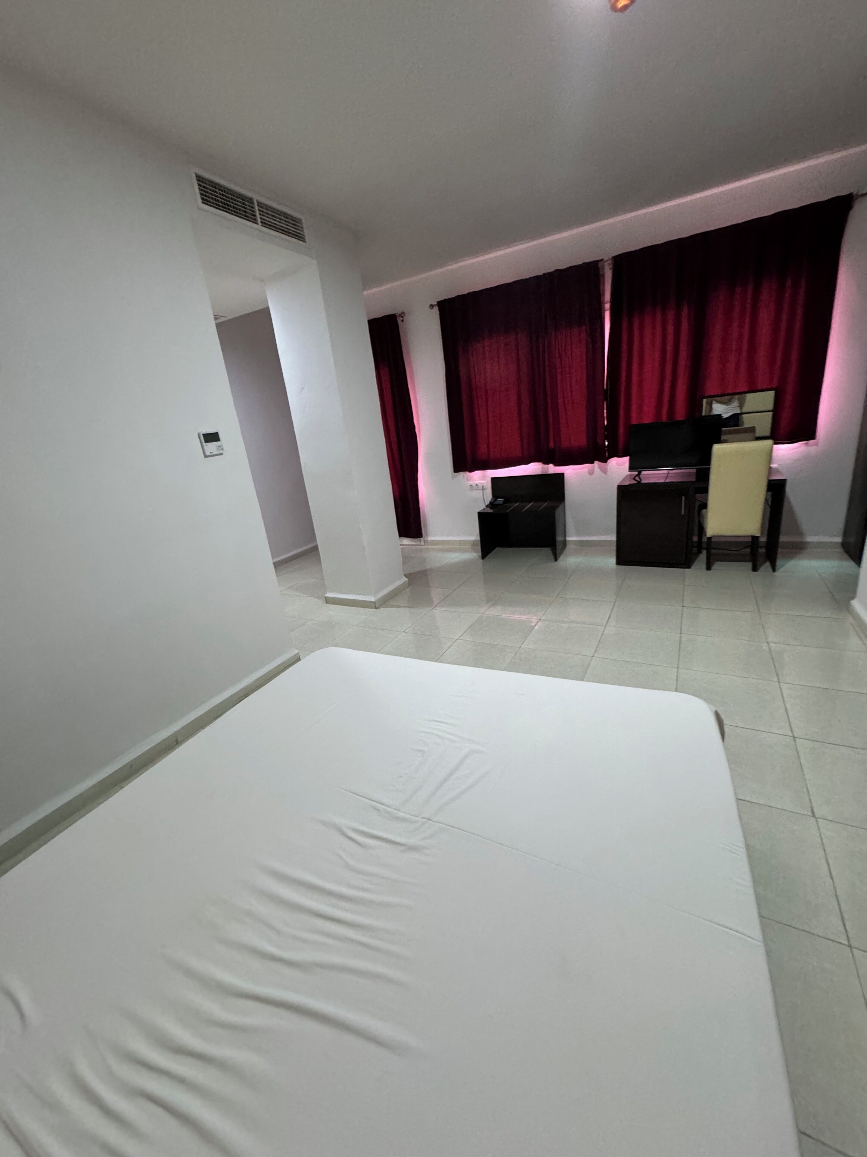 A hotel room with a bed, a desk, a chair, and a window with curtains.