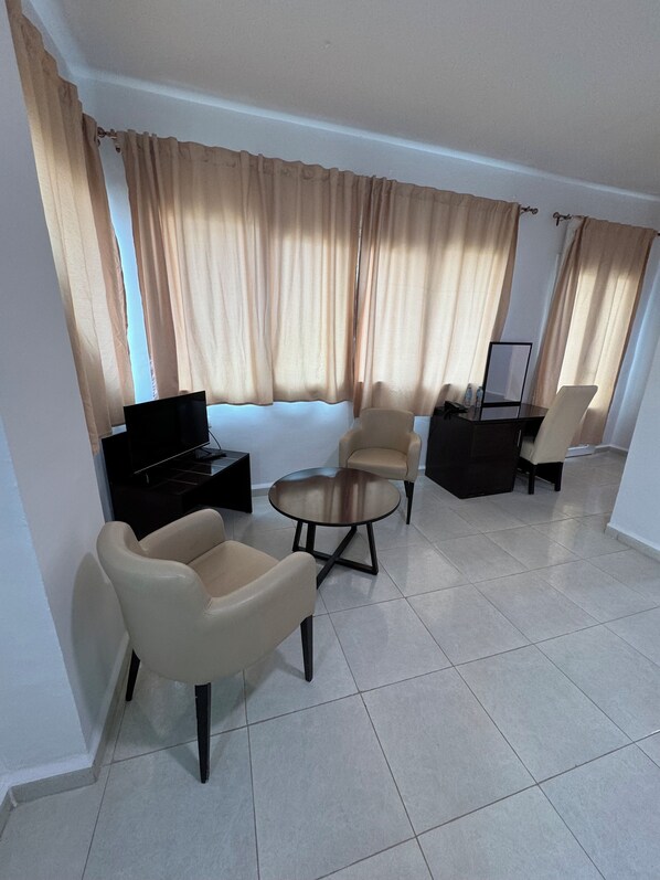 A living room with a sofa, two armchairs, a coffee table, a TV, and a small table with a mirror and some items. - CTM - Le Bateau (Terga)