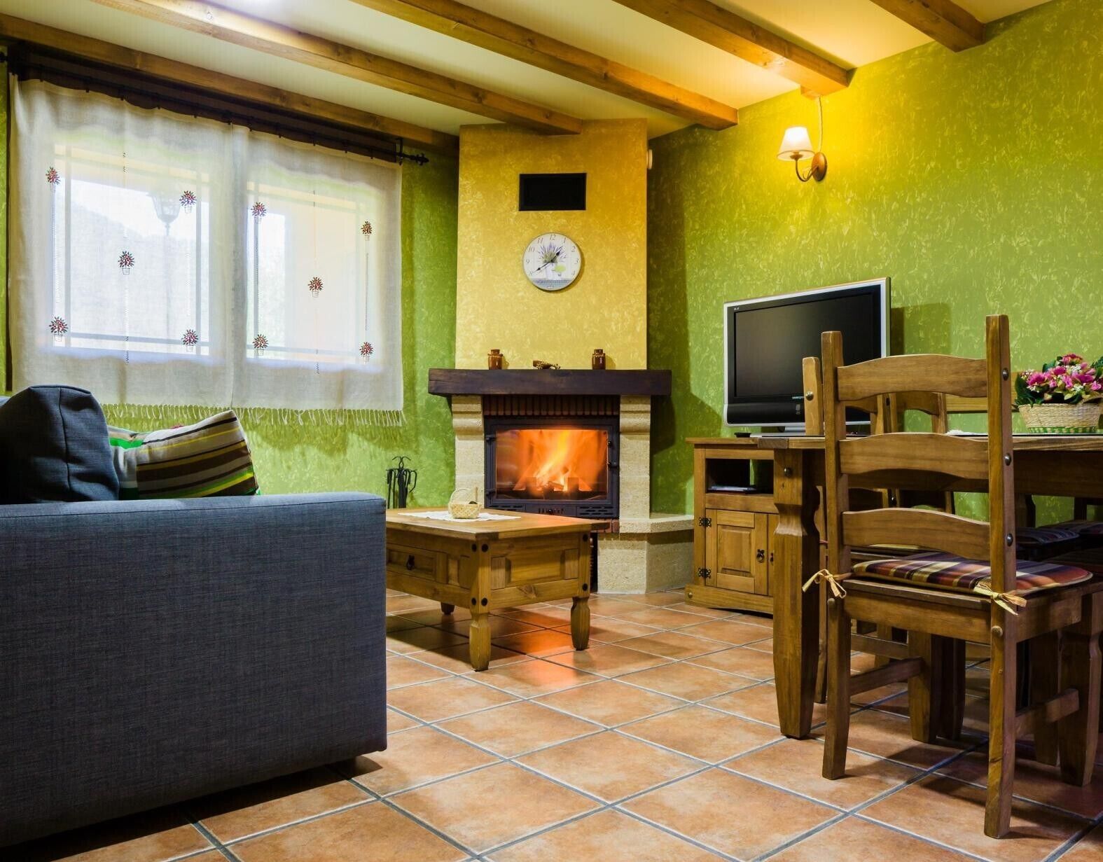 Een gezellige woonkamer met een open haard, een televisie en een bank.