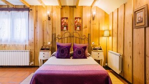 Una habitación con paneles de madera, una cama, dos mesitas de noche, un radiador y una lámpara.