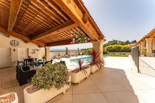 A covered outdoor area with a pool, seating, and potted plants.