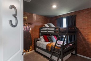 Een kamer met een stapelbed, een bakstenen muur, een poster en een deur met het nummer 3.
