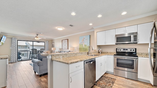 A modern kitchen with white cabinets, stainless steel appliances, and a granite countertop. - Bayview 70 w/Dock & Boat Slip | Dog Friendly | My Beach Getaways (Orange Beach)