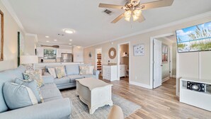 A spacious living room with a light blue sofa, a white coffee table, and a ceiling fan. - Bayview 70 w/Dock & Boat Slip | Dog Friendly | My Beach Getaways (Orange Beach)