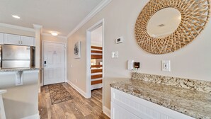A modern kitchen with white cabinetry, a granite countertop, and a large woven mirror. - Bayview 70 w/Dock & Boat Slip | Dog Friendly | My Beach Getaways (Orange Beach)