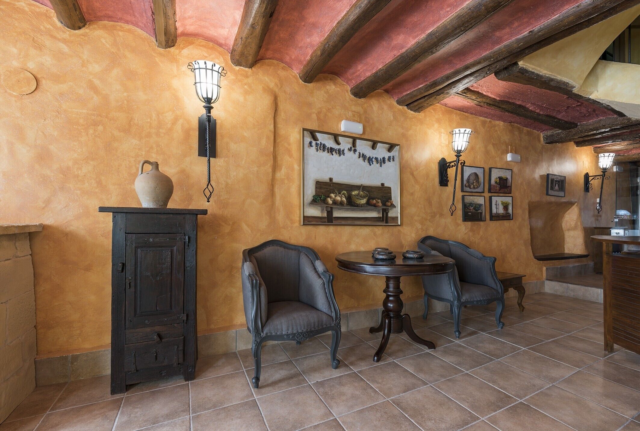 Una habitación con decoración rústica, que incluye un techo de madera, suelo de baldosas y una mesa con sillas.