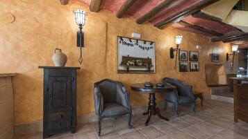 Una habitación con decoración rústica, que incluye un techo de madera, suelo de baldosas y una mesa con sillas.