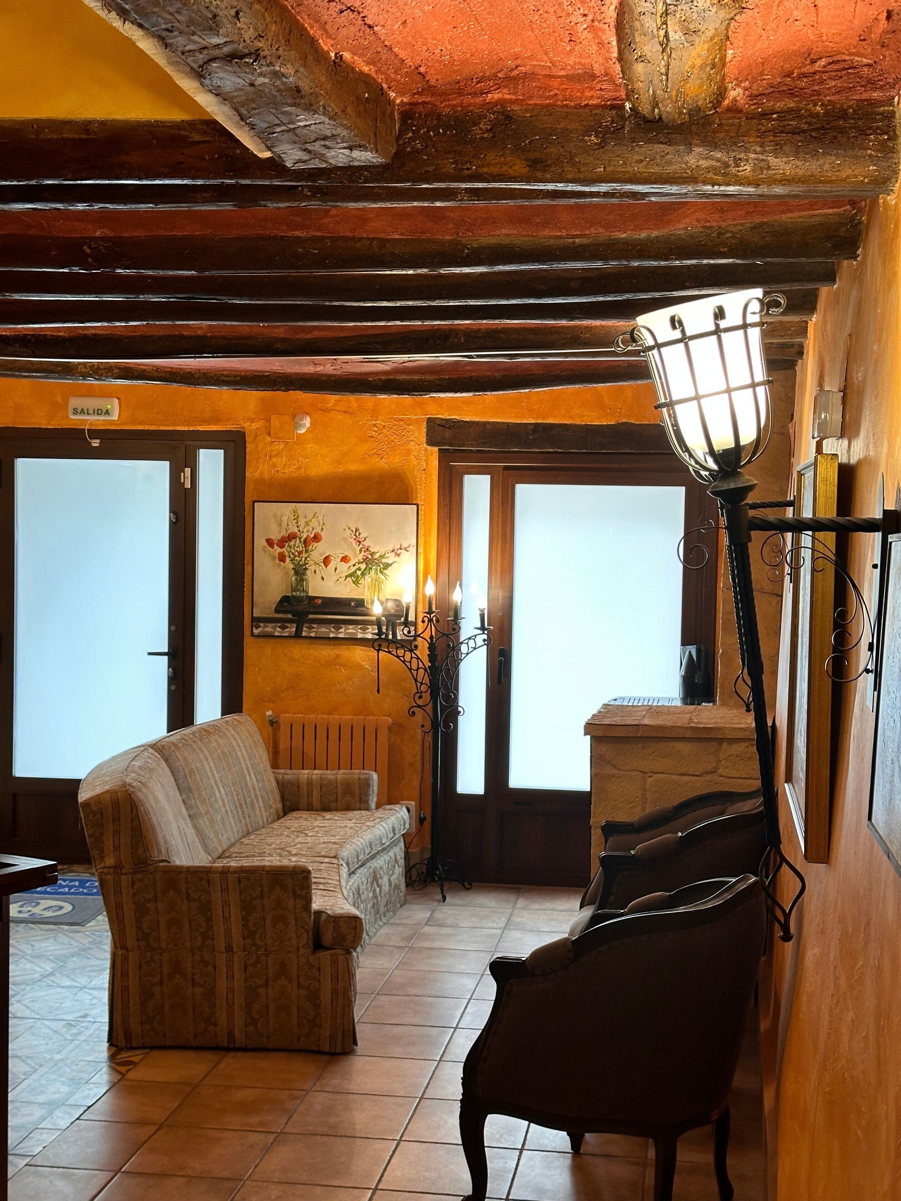 Una habitación con sofá, sillón, lámpara y chimenea.