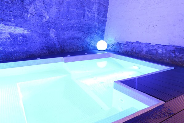 A hot tub with a textured wall and a wooden deck.