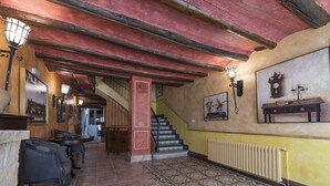 Un corridoio con una scala, pavimento decorato e lampade a parete.