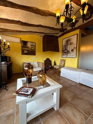 A cozy living room with a white sofa, a coffee table with decorative vases, a fireplace, and wall-mounted artwork.