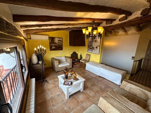 Una sala de estar acogedora con chimenea, un sofá blanco, un sillón de mimbre y una mesa de centro con libros.