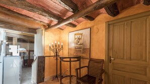 A room with a wooden door, a table with a candelabra, a chair, and a painting on the wall. - Suite 'Las Golondrinas' with Mountain Views and Unlimited SPA Access with Cellar (Lerín)