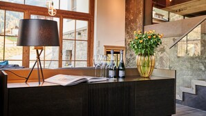 Un espace bar moderne avec une grande fenêtre, une lampe noire, un vase avec des fleurs et des verres à vin.