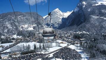 A cable car system over a snowy mountain town with buildings and roads below.