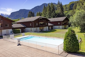 Um hotel com piscina, rodeado por montanhas e vegetação.