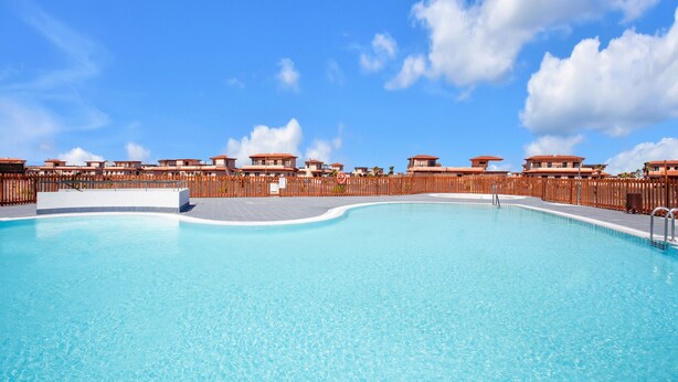 A swimming pool surrounded by a wooden fence, with a clear blue sky above. - Charming Casa Tara: Experience the Magic of Your Perfect Getaway in Paradise (lajares)