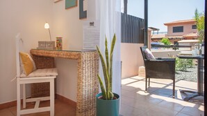 A room with a wicker chair, a small table, a potted plant, and a view of the outside. - Charming Casa Tara: Experience the Magic of Your Perfect Getaway in Paradise (lajares)