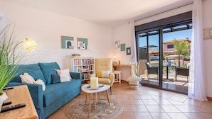 A living room with a blue sofa, a round coffee table, a bookshelf, and a sliding glass door leading to an outdoor patio. - Charming Casa Tara: Experience the Magic of Your Perfect Getaway in Paradise (lajares)