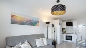 A modern living room with a grey sofa, patterned cushions, a black coffee table, and a painting of a sunset over the ocean. - Vacation Apartment 'Francesco House 1509 Monte Paraiso' with Sea View, Wi-Fi and Air Conditioning (Puerto Rico de Gran Canaria)
