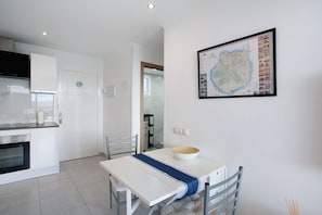 Una cocina moderna con armarios blancos, una mesa de comedor con una cubierta azul y un mapa grande enmarcado en la pared.