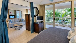 A hotel room with a bed, a sofa, a TV, a desk, and a balcony with a table and chairs. - Maui Banyan T204 1BR condo I Walk to Kamaole Beach (Kihei)