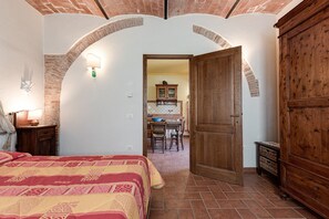 Een slaapkamer met een bed, een houten garderobe en een eethoek met een tafel en stoelen.