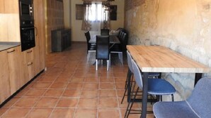 A kitchen with wooden cabinets, a dining area with a table and chairs, and a stone wall. - Country House 'Casa Larralde' with Shared Pool, Wi-Fi and Air Conditioning (Bisimbre)