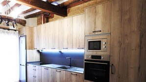 A kitchen with wooden cabinets, a stainless steel sink, a built-in microwave, and an oven. - Country House 'Casa Larralde' with Shared Pool, Wi-Fi and Air Conditioning (Bisimbre)