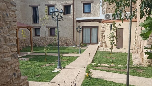 A courtyard with a pathway, stone walls, and a building with multiple windows and a door. - Country House 'Casa Larralde' with Shared Pool, Wi-Fi and Air Conditioning (Bisimbre)