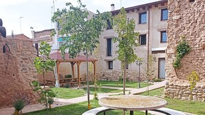 A courtyard with a circular stone table, a pergola, and stone buildings in the background. - Country House 'Casa Larralde' with Shared Pool, Wi-Fi and Air Conditioning (Bisimbre)