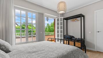 Un dormitorio con cama, armario, perchero y balcón con vistas.