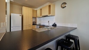 A modern kitchen with wooden cabinets, a stainless steel sink, and a built-in oven. - Kaikoura Luxury Apartments (Kaikoura)