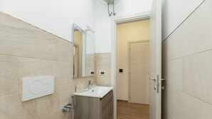 Ein modernes Badezimmer mit einem Holzbadezimmerhocker, einem Spiegel und einer Leuchte darüber.