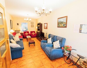 Un salon avec deux canapés, une table basse, un téléviseur et un vélo.