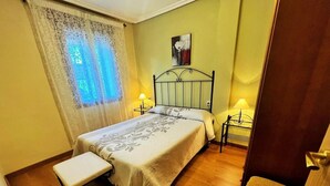 Une chambre à coucher avec un lit, des lampes de chevet, un banc et un tableau au mur.