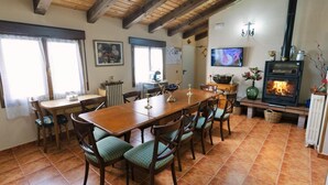Un coin repas avec une table et des chaises en bois, une cheminée et un téléviseur fixé au mur.