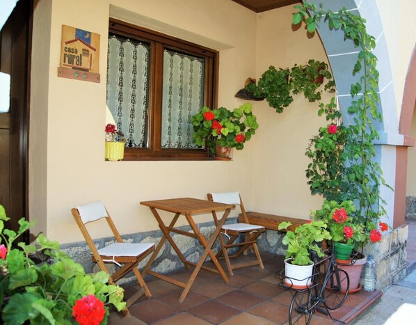 Un espace extérieur aménagé dans un style rustique, avec une table et des chaises en bois, des plantes en pot et un vélo.