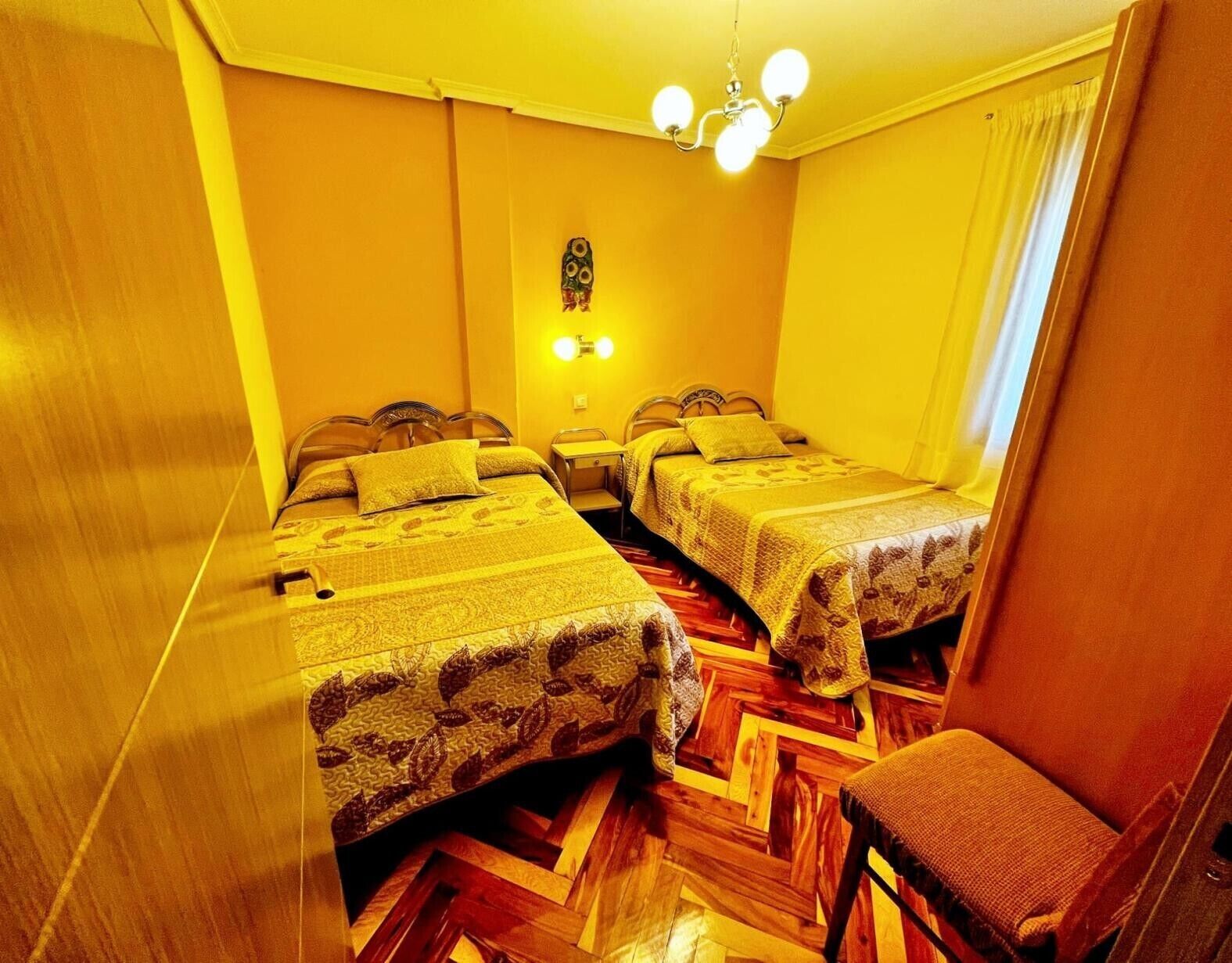 Ein Zimmer mit zwei Betten, einem Sessel und einer Deckenleuchte.
