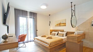 A modern bedroom with a wooden bed, a desk, a chair, and a large window with curtains.