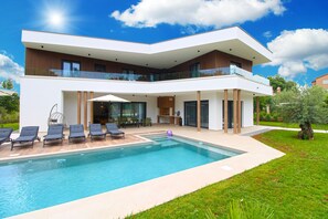 Une maison moderne à deux étages, dotée d’une piscine, d’un espace extérieur aménagé et d’un jardin bien entretenu.