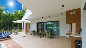 A modern outdoor lounge area with a pool, seating, and a pergola providing shade.