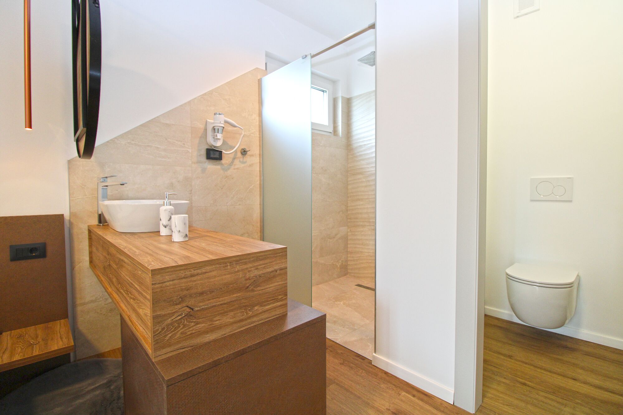 A modern bathroom with a wooden vanity, a glass shower enclosure, and a white toilet.
