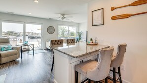 A spacious living area with a large window, a ceiling fan, and a dining area with bar stools. - Little Egg Harbor Township Retreat w/ Private Dock (Little Egg Harbor Township)