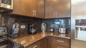 Una cocina moderna con electrodomésticos de acero inoxidable, encimeras de granito y armarios de madera.