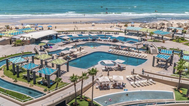 Un resort con varias piscinas, tumbonas y sombrillas.